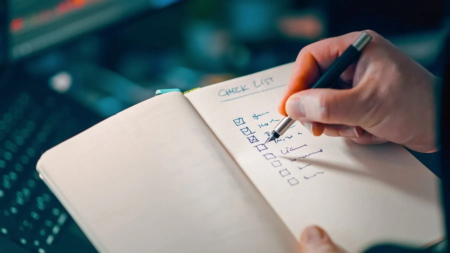 A hand ticking items off a handwritten checklist in a notebook