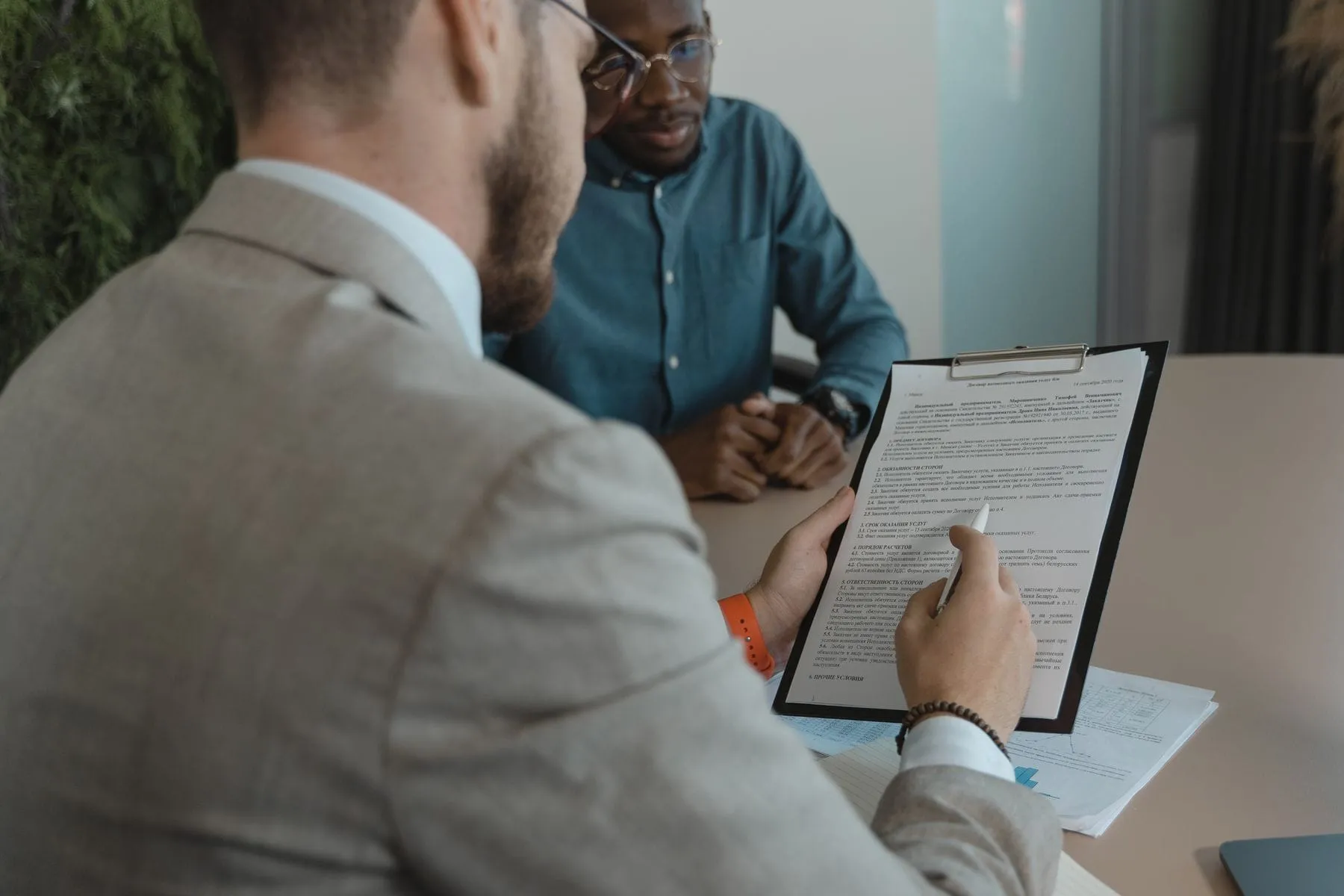 Two people reviewing and signing documents across a desk